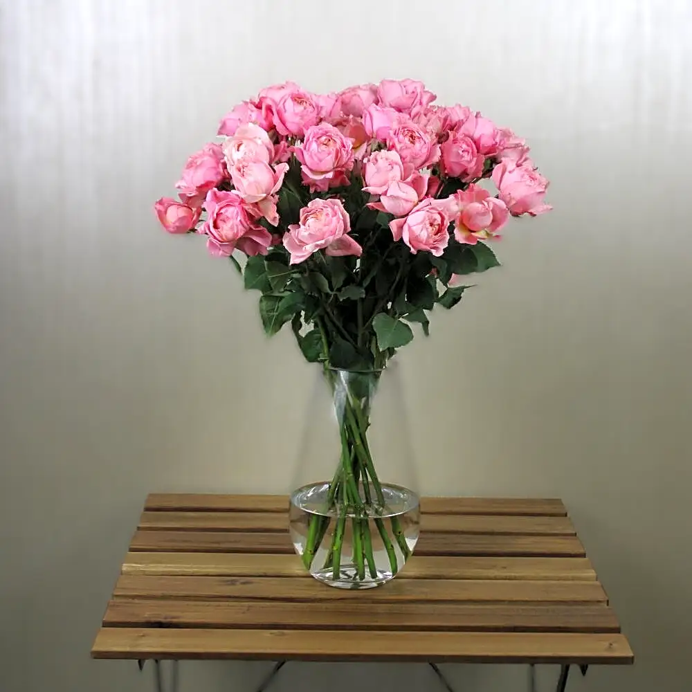 A vase of simple pink roses with white stones
