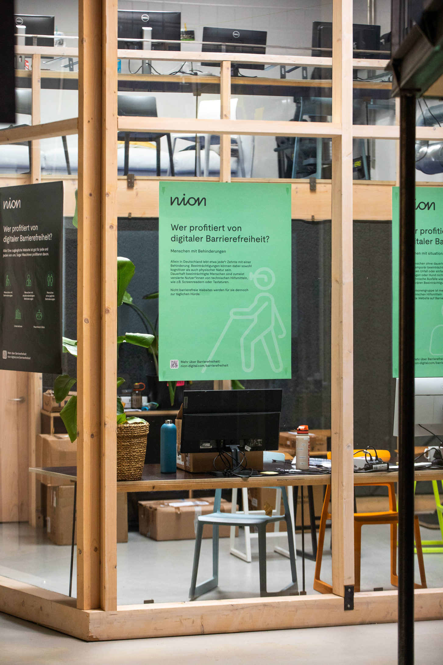 Blick in einen verglasten Raum im Impact Hub München an dessen Glaswand Plakate mit Infos zu digitaler Barrierefreiheit von nion digital hängen / Bildquelle: Lumen & Letter