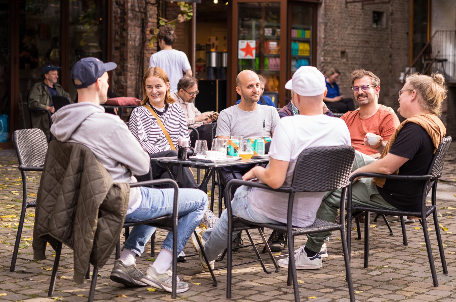 Mehrere Personen sitzen lächelnd um einen Tisch in einem Innenhof