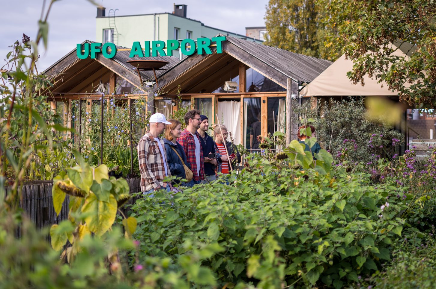 Mehrere Personen stehen auf einer dicht begrünten Dachterrasse