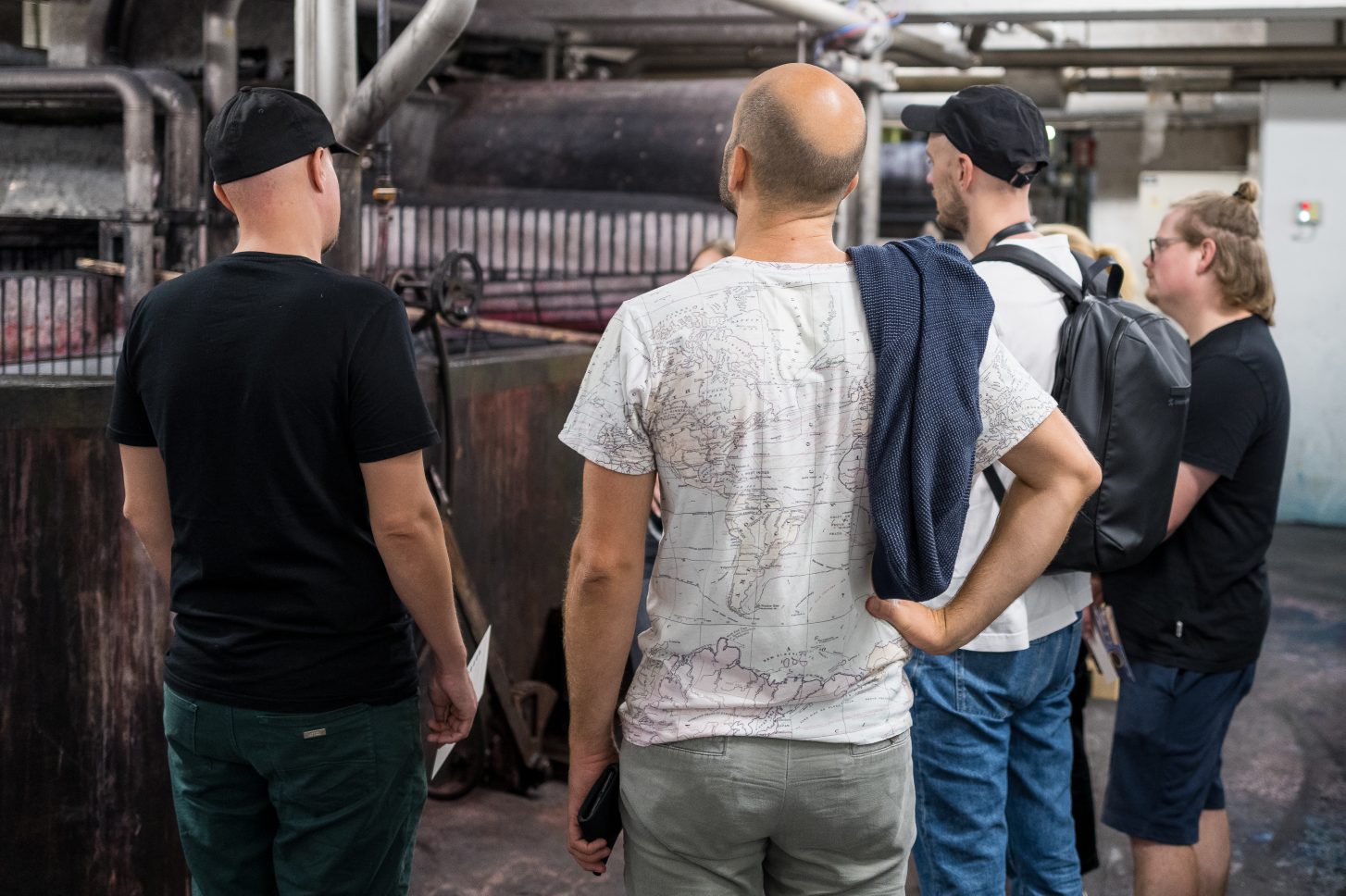 Mehrere Personen stehen mit dem Rücken zur Kamera und blicken auf eine Maschine