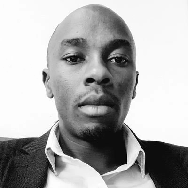 a black and white photo of a njoguamos in a suit and with a serious look on his face