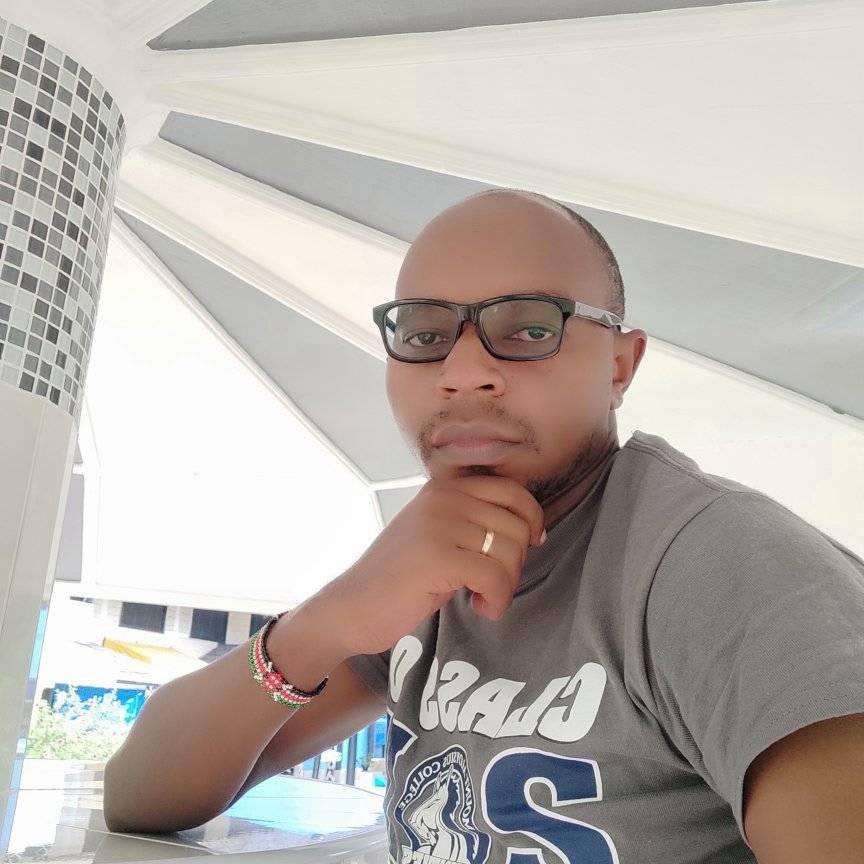 a man sitting at a table and a building in the back ground