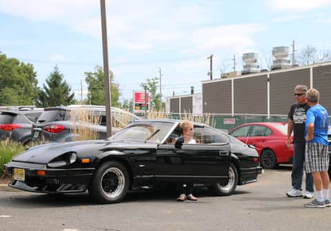A black 280ZX with front spoiler, side skirts, rear spoiler and silver rims with black spokes