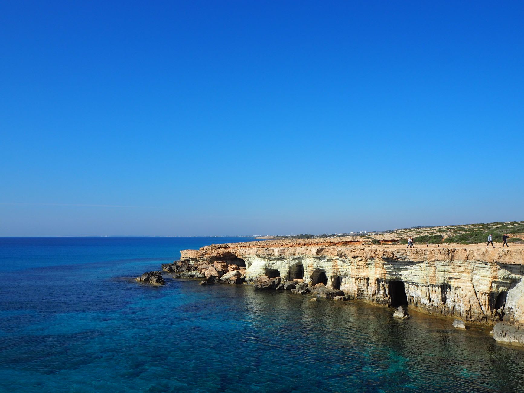 Falaises calcaires percées de grottes marines sur le littoral sud-est de Chypre, mer turquoise et ciel bleu