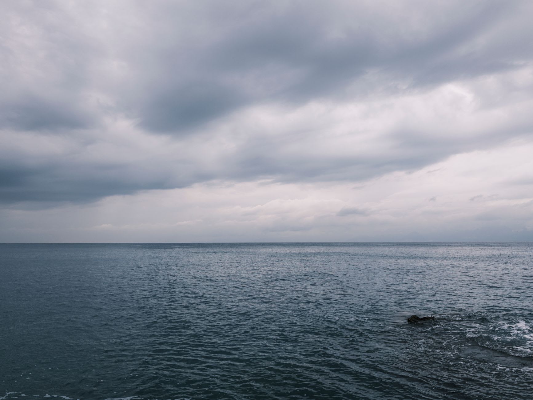 Étendue de mer sombre sous un plafond de nuages bas, sans un baigneur jusqu’à l’horizon