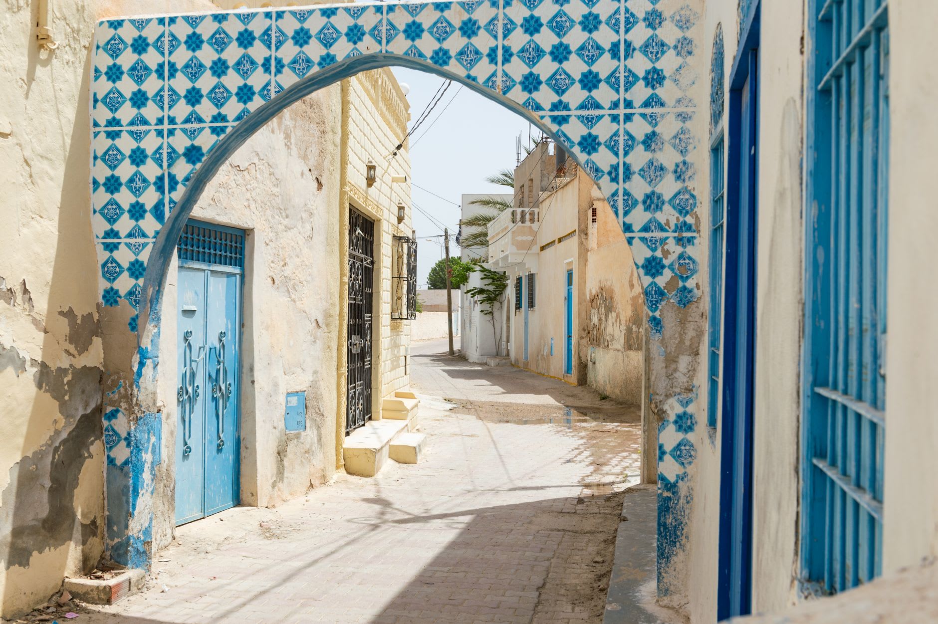 Arche couverte de carreaux de faïence bleue et blanche au-dessus d’une ruelle bordée de portes bleues