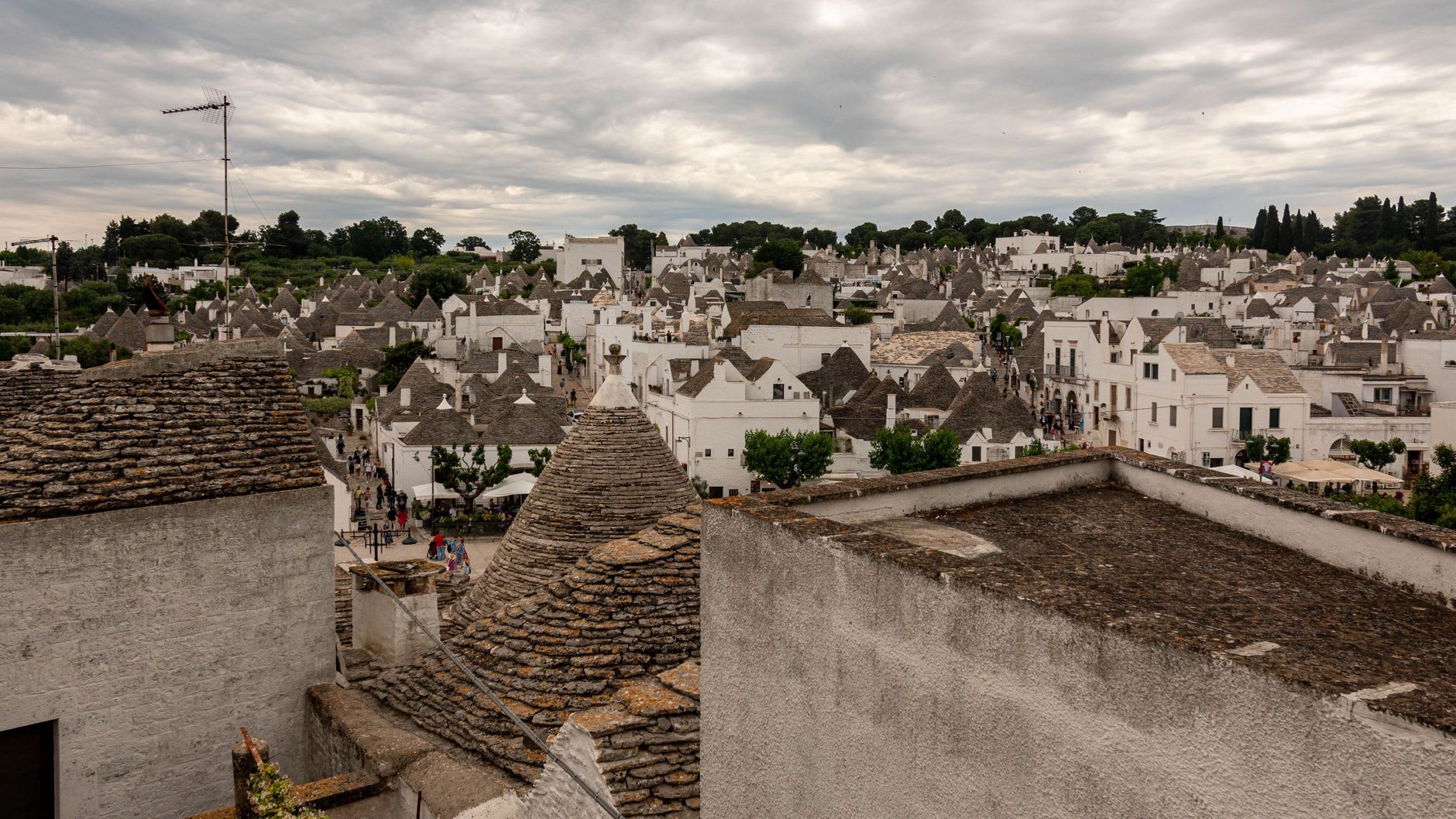 Toits coniques en pierre sèche à perte de vue et files de visiteurs dans les ruelles en contrebas, ciel gris