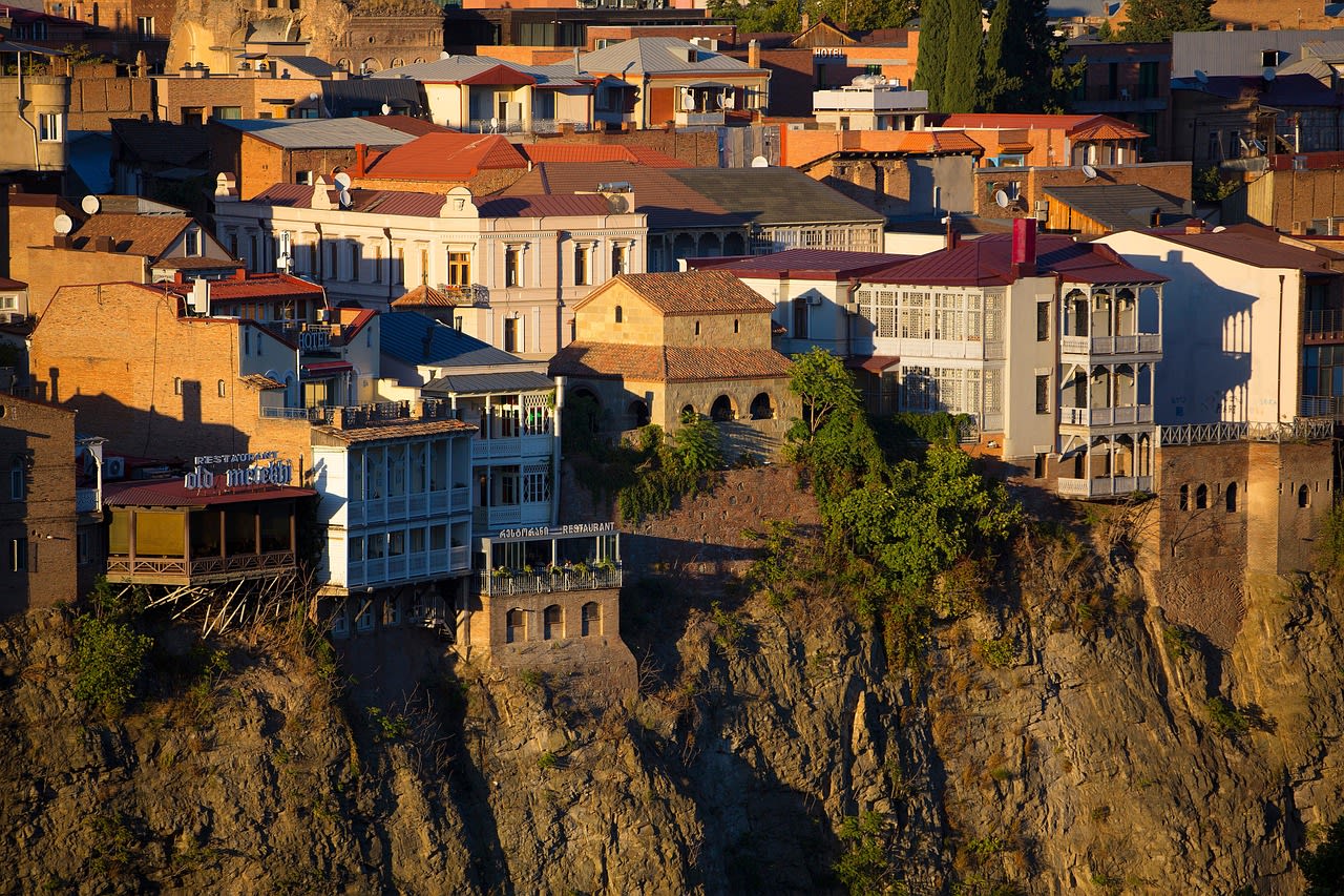 Maisons à balcons de bois accrochées à la falaise au-dessus de la Mtkvari, restaurants de la vieille ville au soleil couchant
