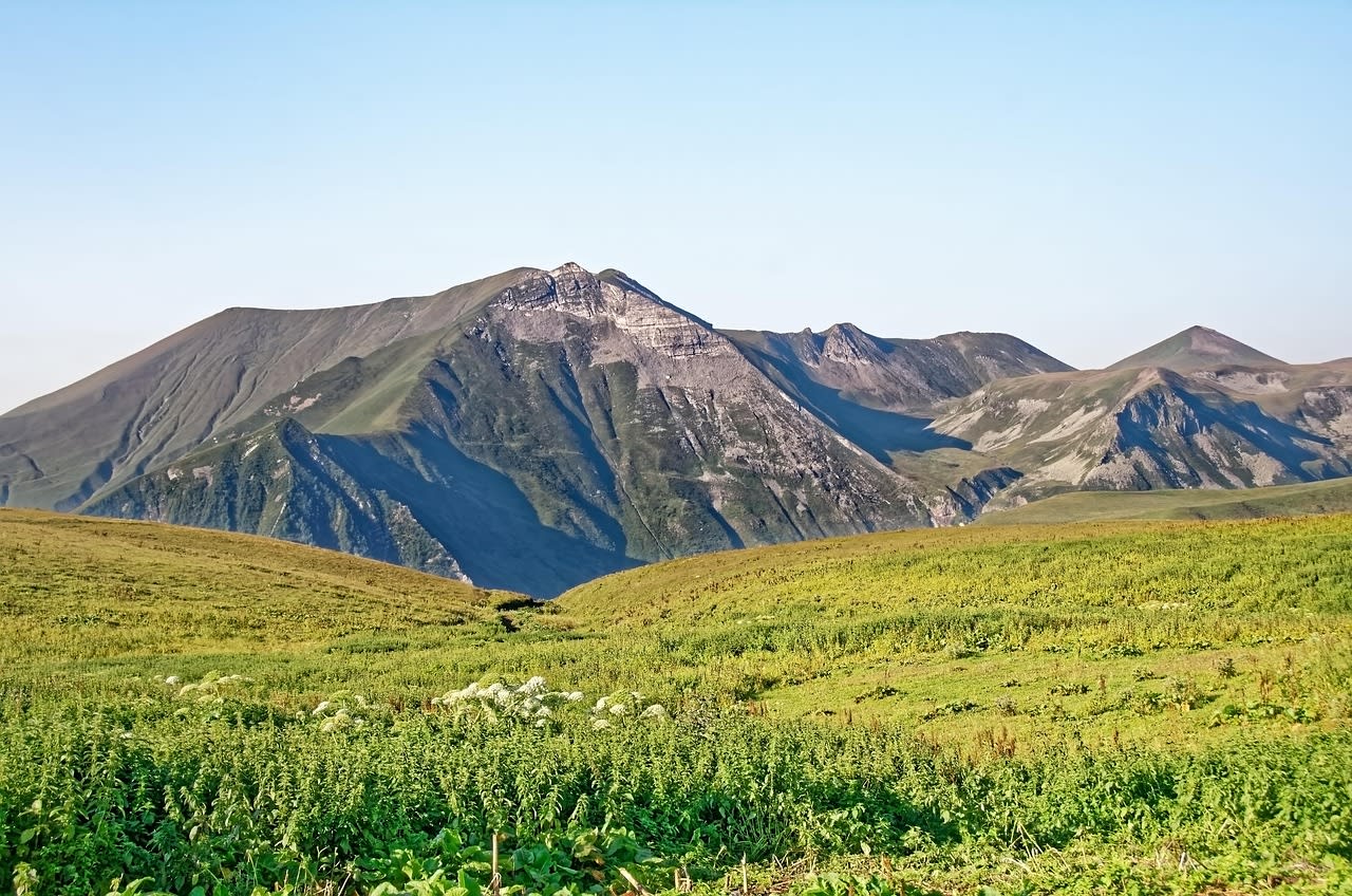 Crête herbeuse du Grand Caucase sans sentier balisé ni panneau, prairie d’alpage au premier plan