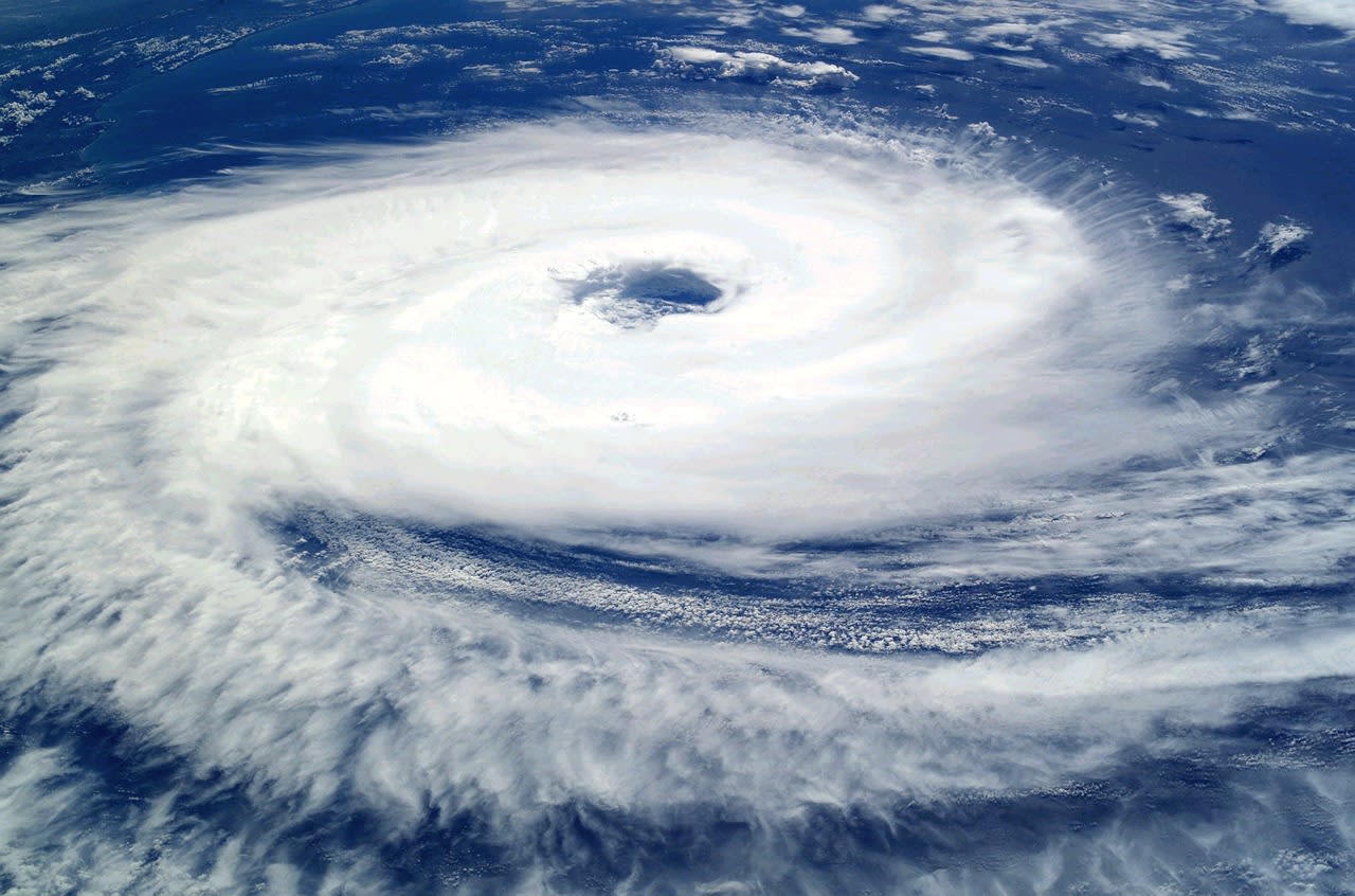 Immense cyclone tropical vu de l’espace, œil sombre bien dessiné au cœur d’une vaste spirale de nuages blancs sur l’océan