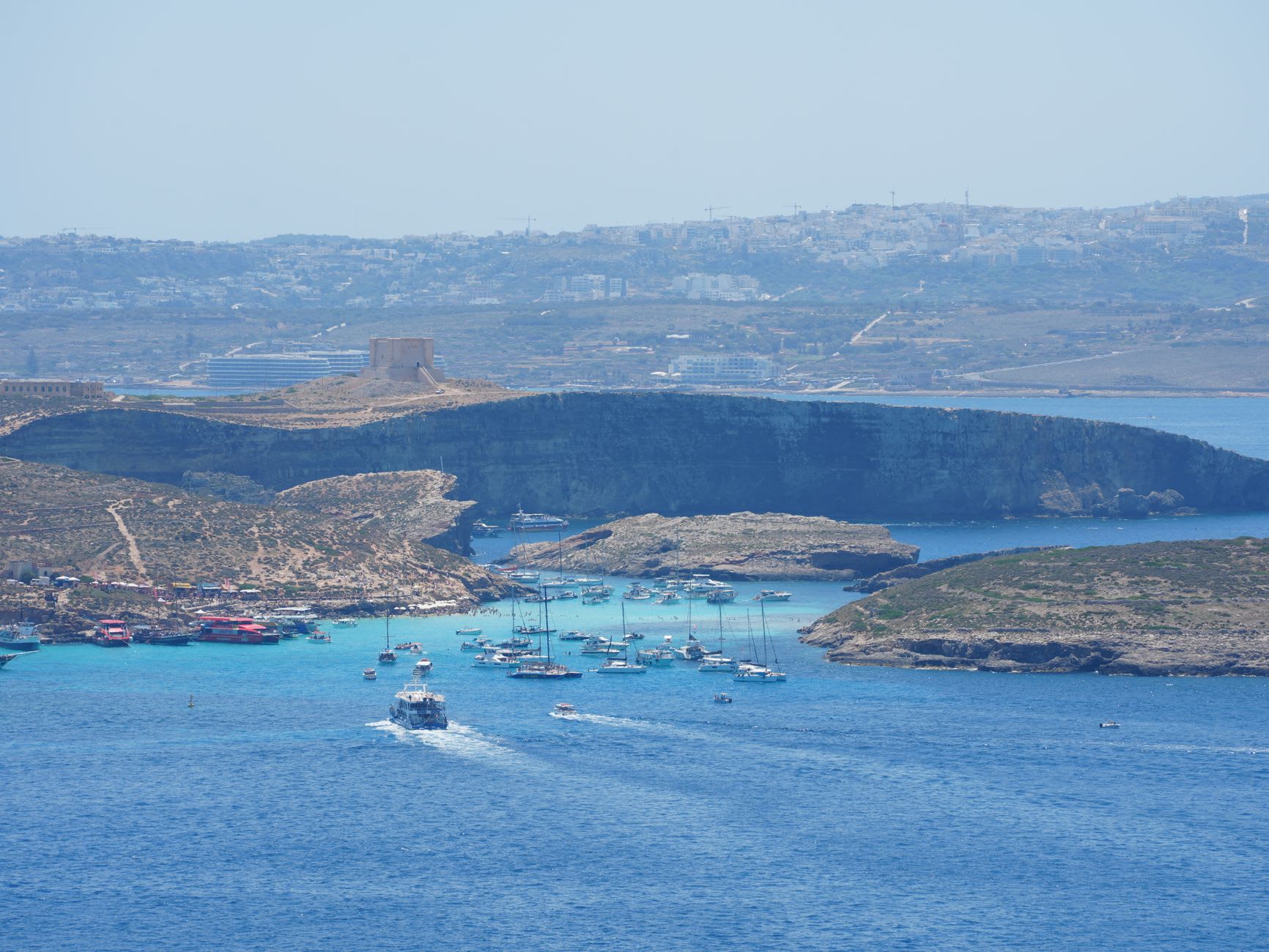 Vue aérienne du Blue Lagoon de Comino, eau turquoise saturée de bateaux d’excursion et de voiliers à l’ancre