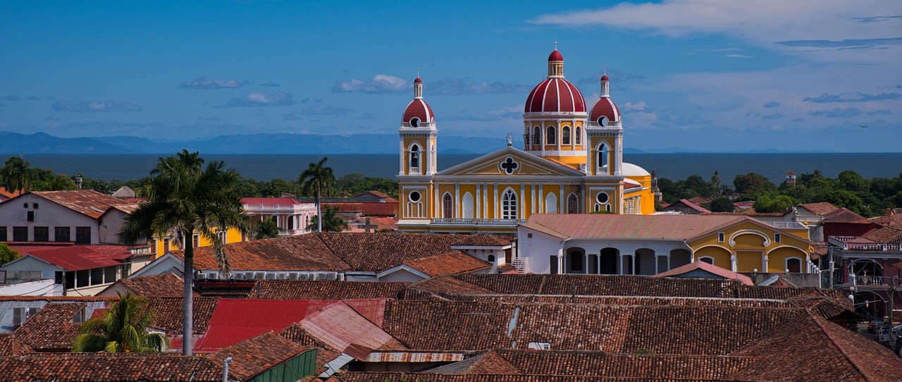 Toits de tuiles rouges de Granada et cathédrale jaune à dômes rouges devant le lac Nicaragua