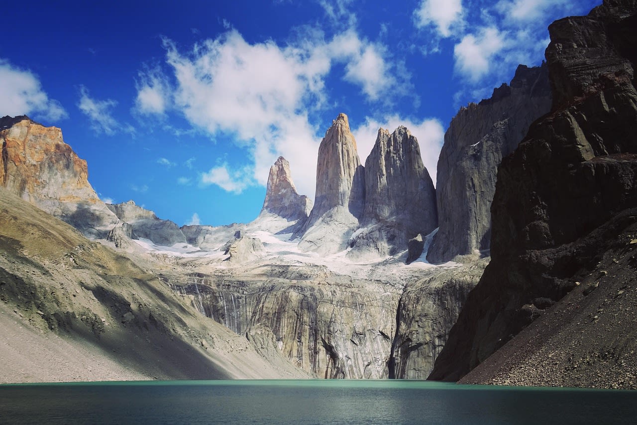 Les trois tours de granite du massif du Paine au-dessus d'une lagune turquoise, sous un ciel de traîne