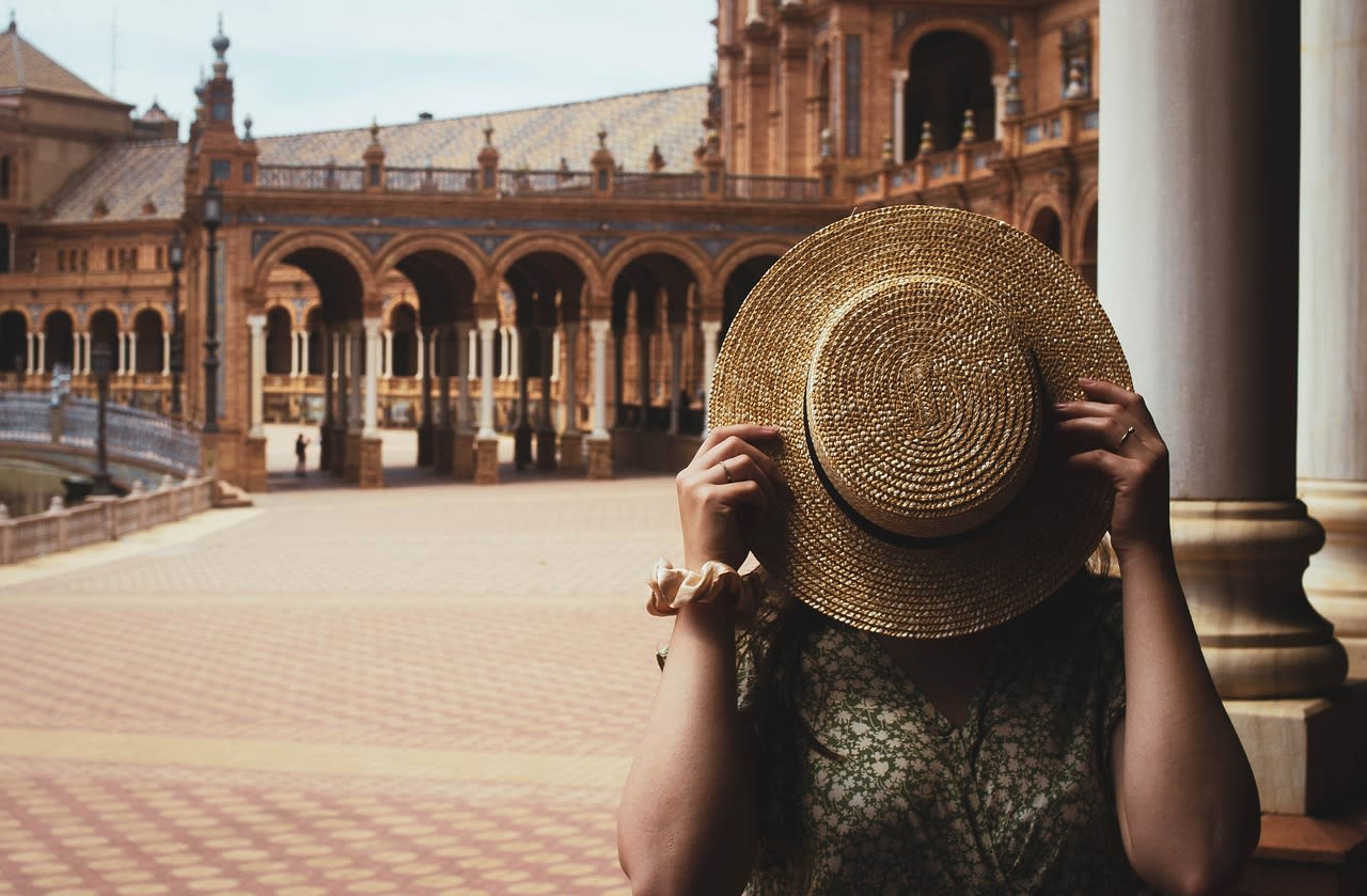 Voyageuse au chapeau de paille devant les arcades de la plaza de España