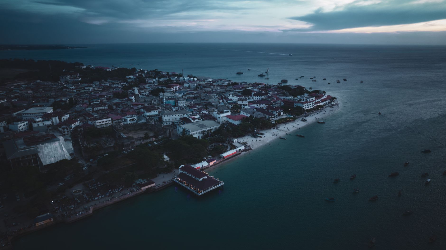 Vue aérienne de Stone Town au crépuscule sous un ciel lourd de nuages gris, boutres au mouillage