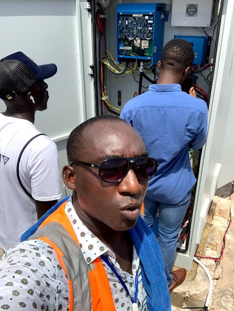 Technicien ENERCOS devant une armoire d'énergie en cours de mise en service (onduleur et régulation), l'équipe au travail.