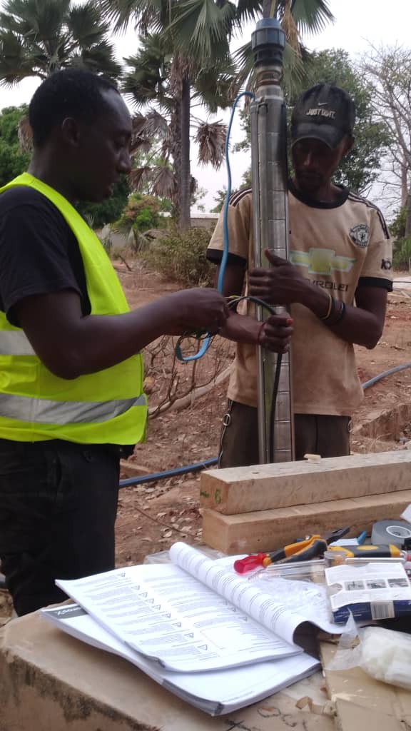Deux techniciens ENERCOS préparant une pompe immergée avant sa descente dans un forage.