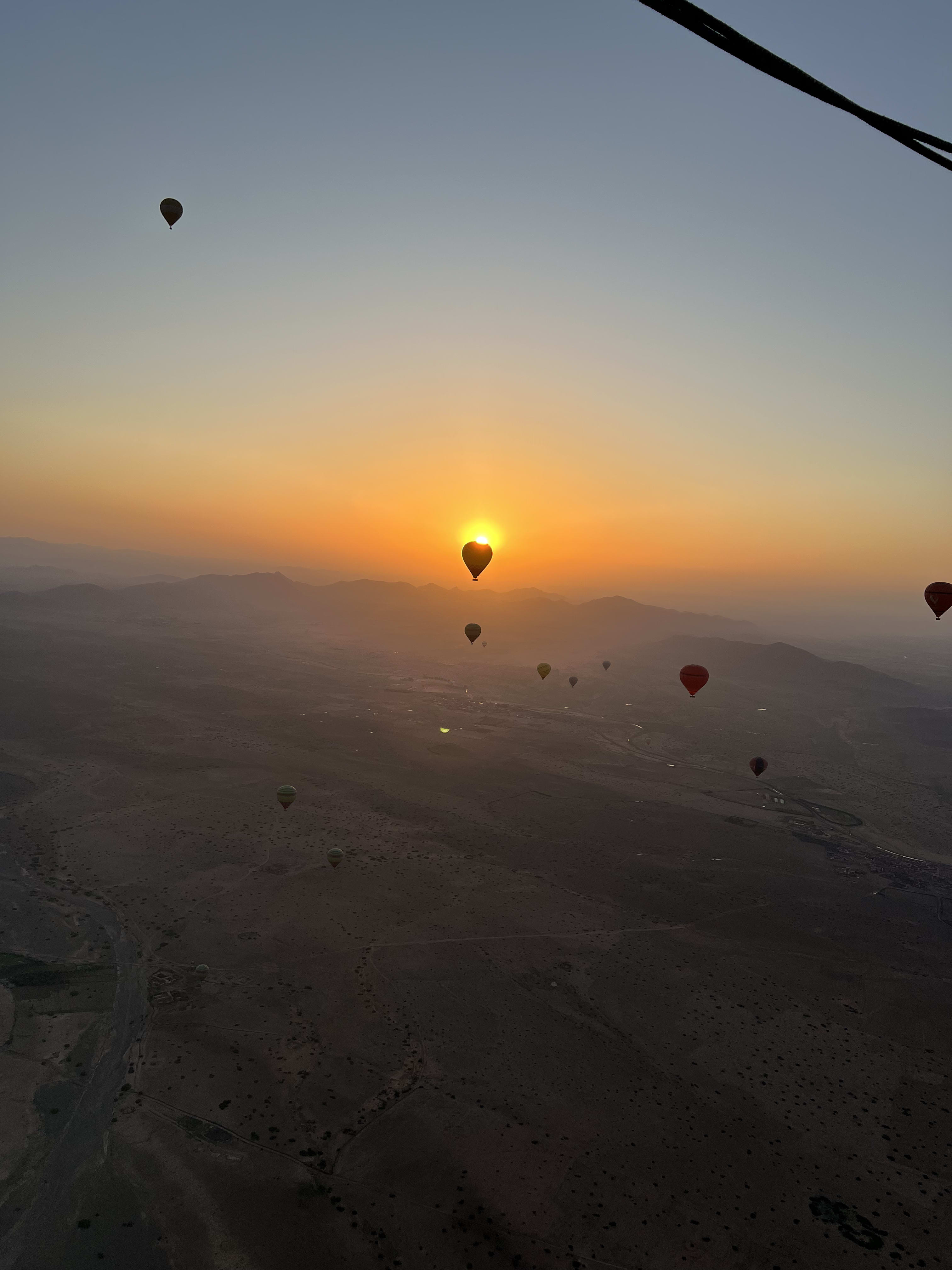 Soleil derrière une montgolfière au-dessus des collines