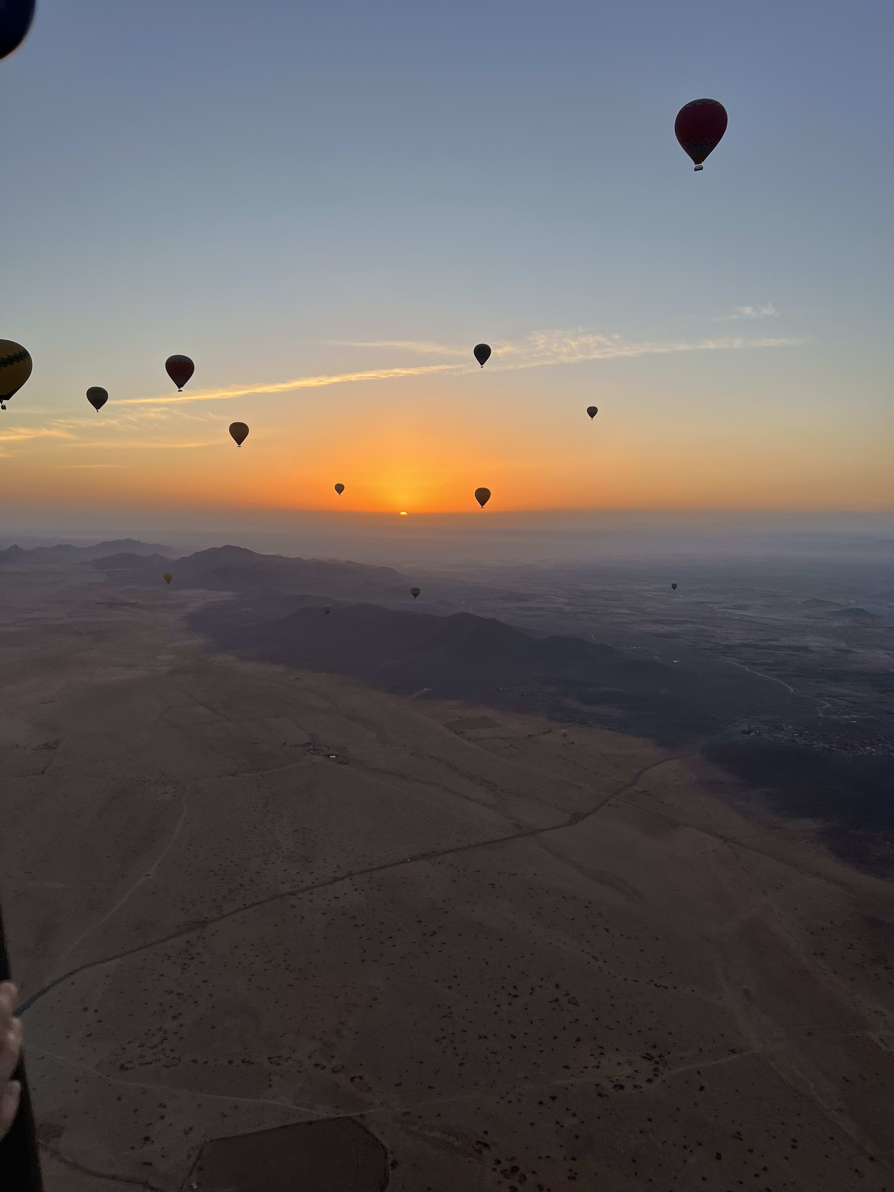 Montgolfières dans le ciel orange du lever du soleil près de Marrakech