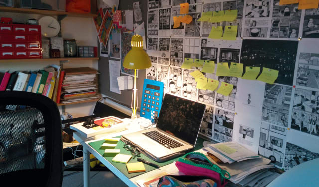 Workspace showing a laptop in front of a wall full of illustrations