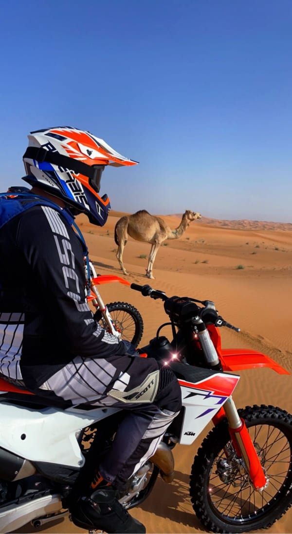 Motorbike rider meets camel in desert