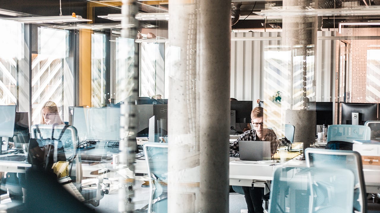 office scene with large pillars and 2 workers on laptops