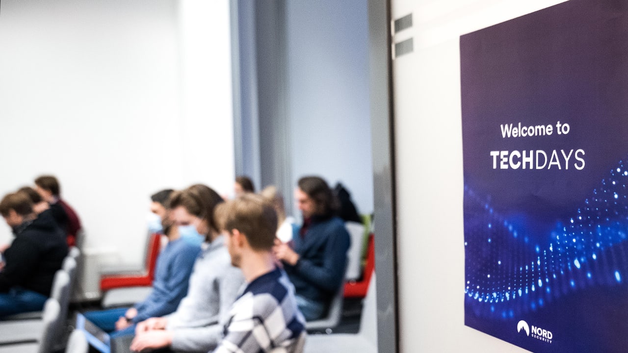 techdays poster hangs on a wall while the audience sits in the event room