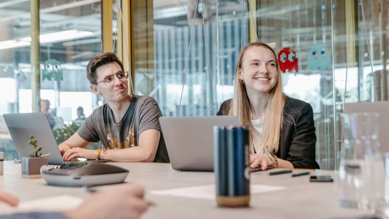 2 people smiling and working on laptop