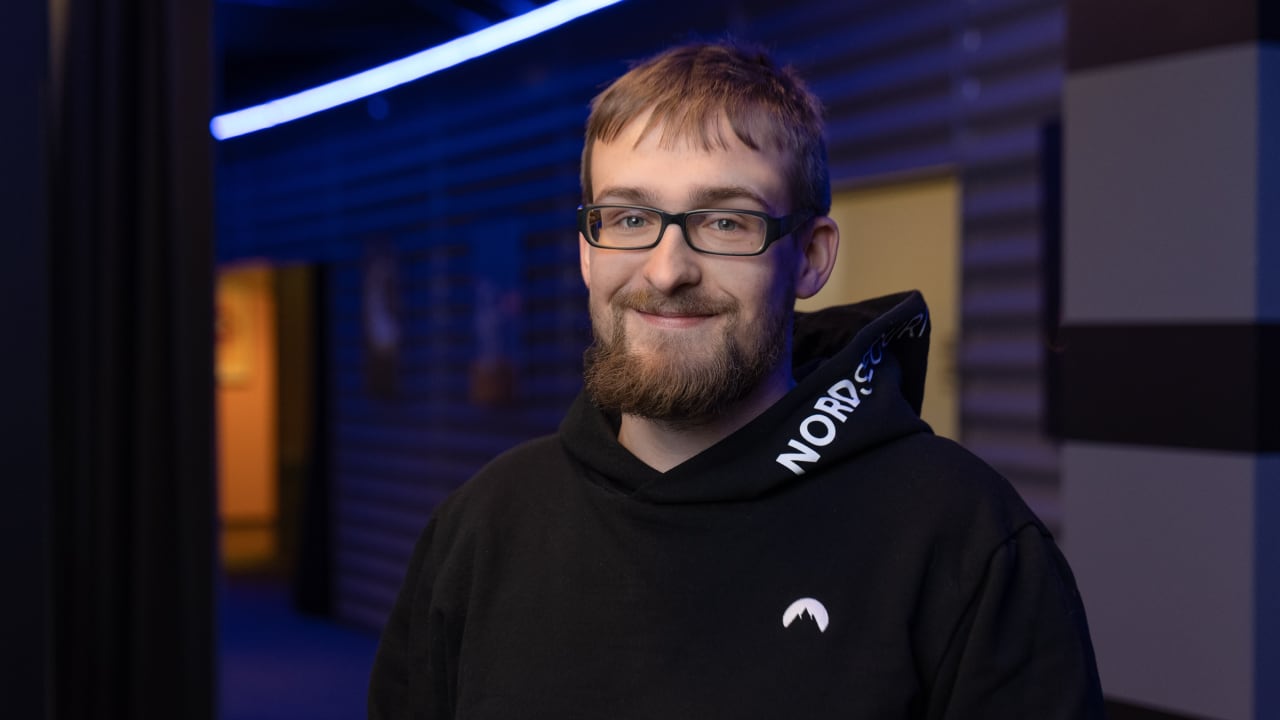 smiling, bearded engineer wearing a black hoodie and glasses