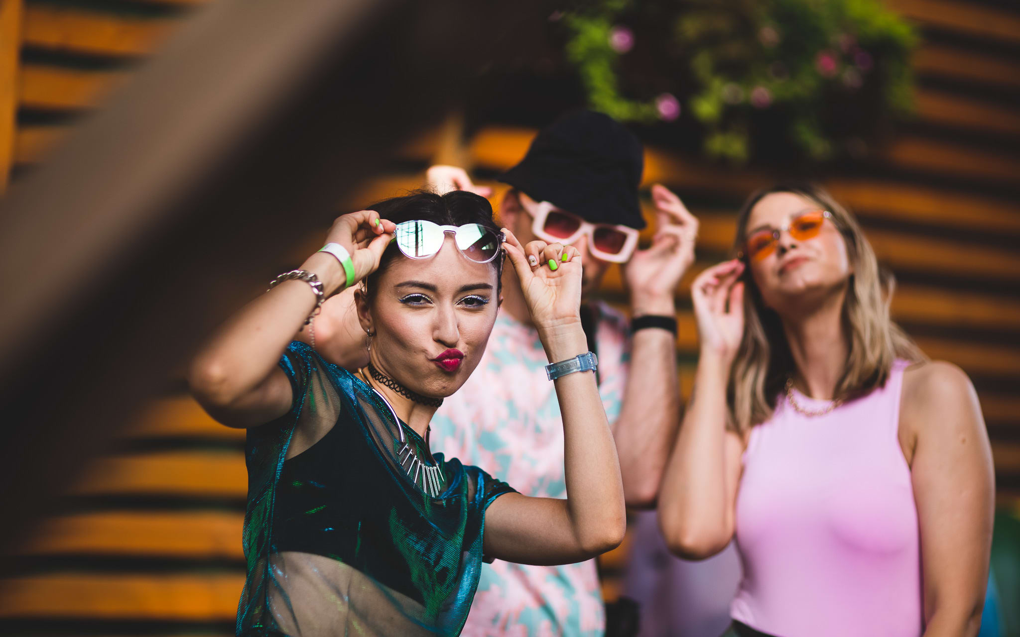 Young woman wearing sunglasses and festival bracelets poses for camera 