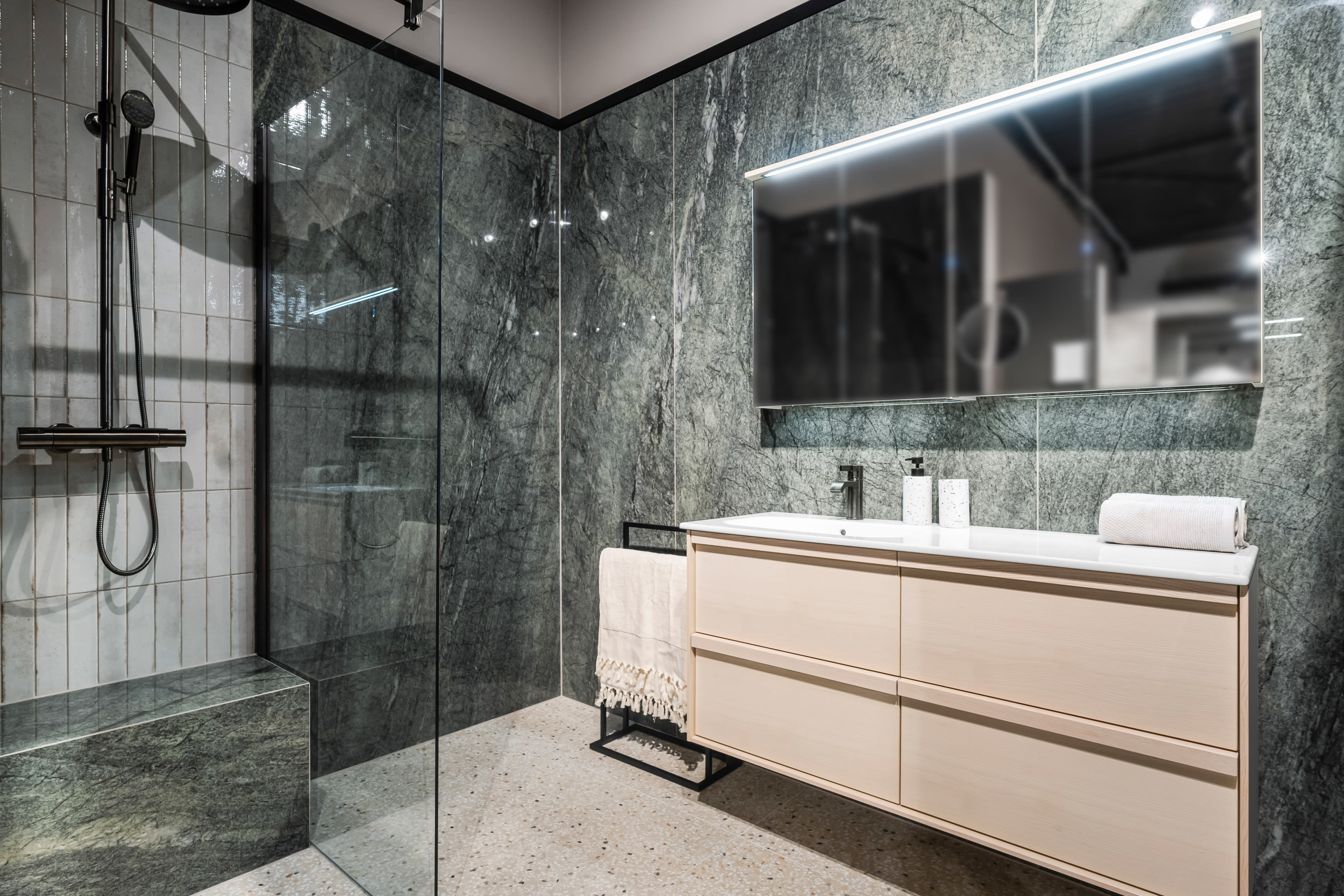 Baderom med grønne marmorfliser som veggfliser og terrazzo gulvfliser og Haven baderomsinnredning.