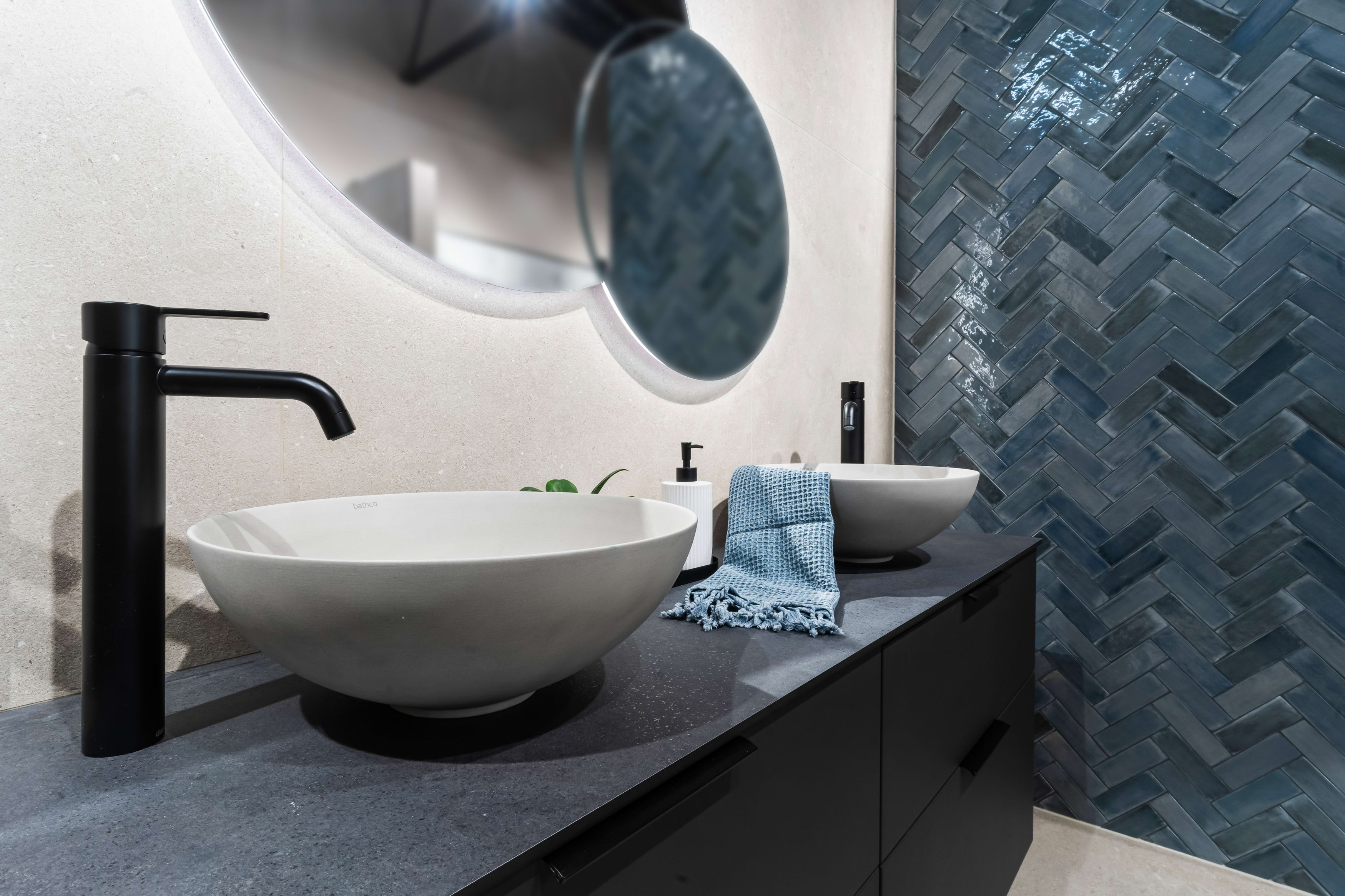 Baderom med bolleservant og servantbatteri i matt sort. Blå dekorfliser lagt i fiskebein.