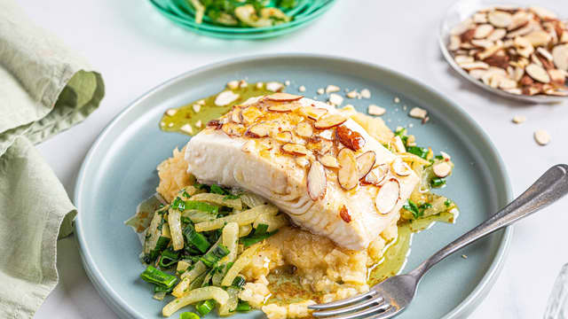 Anrett sellerirotmos, fennikel og vårløk på to tallerkener. Legg på fisken og topp med smeltet hvitløkssmør.