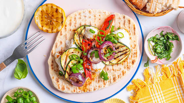 Riv opp mozzarella i passende biter, og legg dem på yoghurtbrødene. Topp med grillede grønnsaker, hot honey og vårløk.