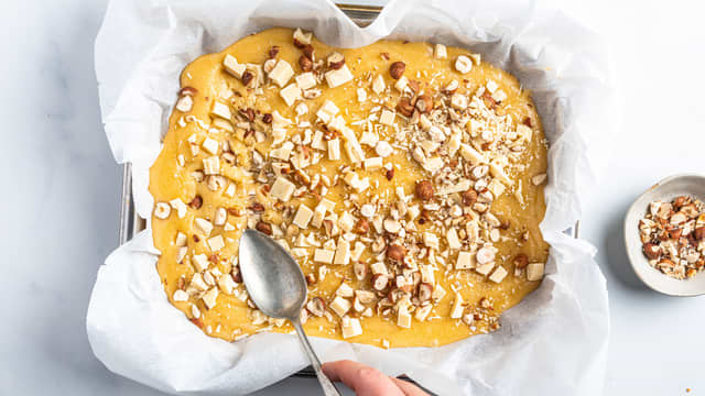 Hakk nøtter og hvit sjokolade i biter og ha over røren.