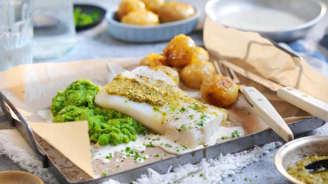 Server torsken med ertepuré, ovnsbakte poteter og saus.