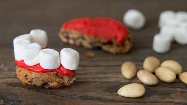 Plasser mini-marshmallows som tenner langs kanten av kjeksen. Smør kremostblandingen på den andre halvdelen av kjeksen og plasser den på toppen av "tennene".