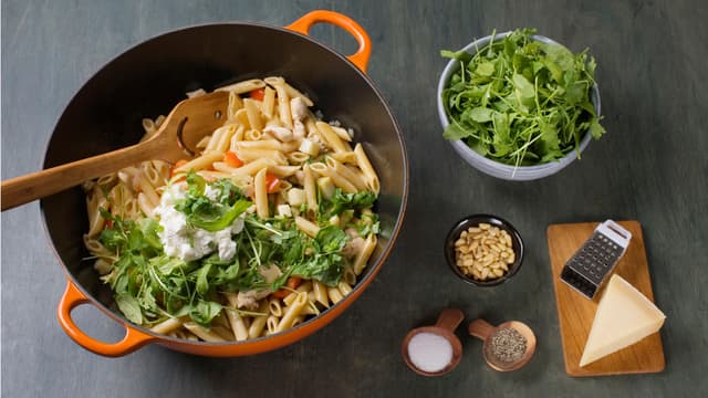 Vend inn kokt pasta, ricotta, ruccula og basilikum. Krydre med salt og pepper. Strø over pinjekjerner og riv over parmesan før servering.