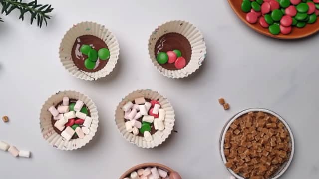 Hell litt smeltet kokesjokolade i bunnen av muffinsformene. Fyll muffinsformer med noen mini marshmallows og Non Stop.