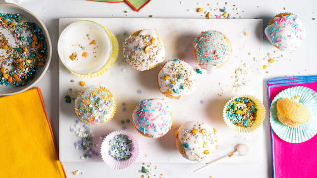 Fordel melisglasur på muffinsene med en skje, og ha på ønsket topping eller strøssel.