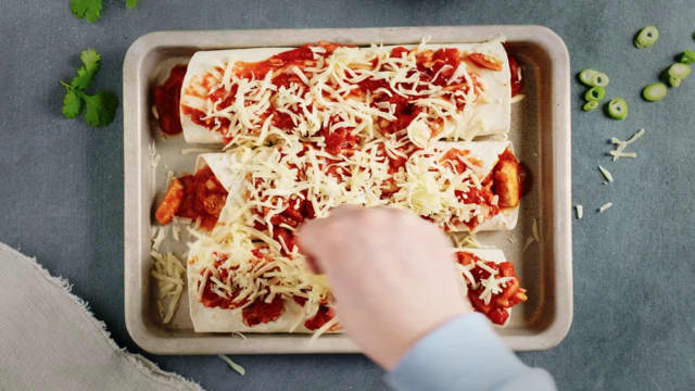 Legg et par spiseskjeer kjøttdeig i hver tortilla, rull sammen og legg i ildfast form. Når du har fylt alle tortillaene, drysser du over revet ost.