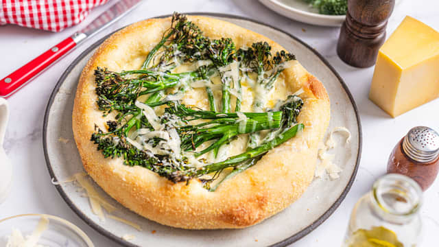 Topp pizzaen med grillet brokkolini, høvlet bufarost, litt olivenolje og chiliflakes.