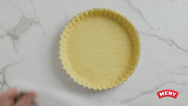 Finn frem en terteform eller paiform og press deigen godt utover bunnen. Bunnen skal være helt tynn, og vil blåse seg litt opp under steking. Stikk mange små hull i tertebunnen med en gaffel.