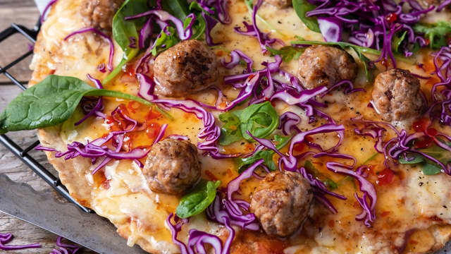 Topp pizzaen med babyspinat og rødkål kuttet i tynne strimler før servering.