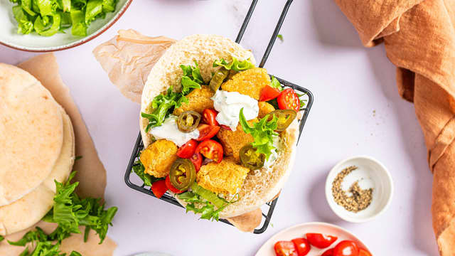 Server falafel i pitabrød med tomat, litt frisk salat og tzatziki.