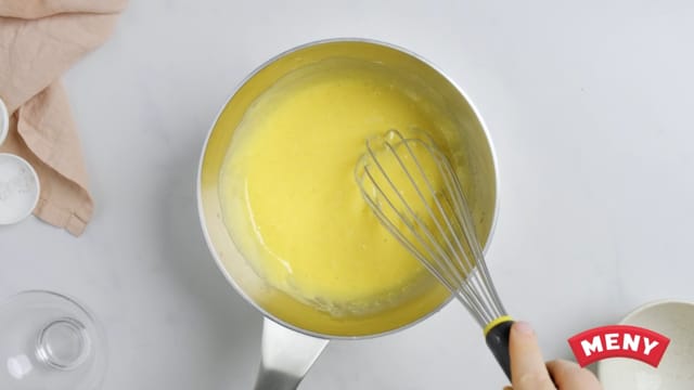 Sett på medium varme og kok opp blandingen mens du hele tiden rører langs bunnen. La kremen koke i 2 minutter før du tar kjelen av varmen og pisker inn smøret med en visp. Sett den gule kremen til avkjøling.