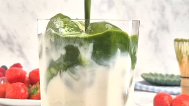 Ha jordbærpuréen i et glass. Fyll glasset med isbiter, hell over melk og til slutt matchen.