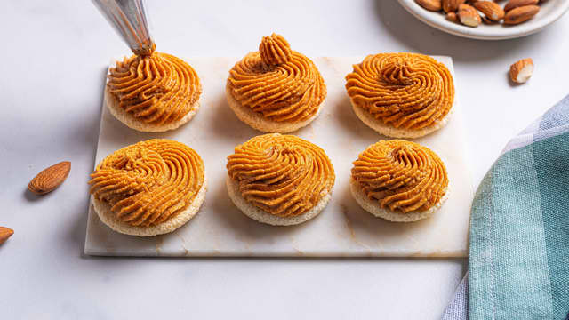 **Fyll makronene:** Ta karamellen ut av kjøleskapet. Visp i noen minutter med en håndmikser, til den blir lysere og stivere. Bruk en slikkepott og ha karamellen over i en sprøytepose. Sprøyt fyllet mellom to makronskall.