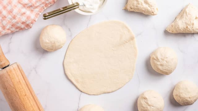 Kjevle ut hver bolle til tynne lefser. Dekk dem til med et kjøkkenhåndkle og la dem heve i ytterligere 10 minutter.